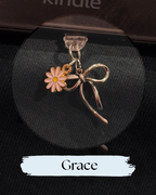 Dust plug for Kindle or e-reader,  charm featuring a pink daisy flower with a yellow center and a metallic silver bow above it, for Kindle, Kindle Accessory, One More Chapter