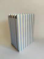 One More Chapter Premium Kindle Case in Rainy Sunday – five dusty blue and cream stripe folios fanned upright, top-down spine view