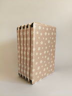 One More Chapter Premium Kindle Case in Petals & Prologues – six blush pink floral folios fanned upright, front-facing angled view
