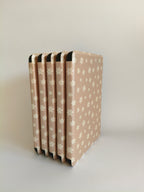 One More Chapter Premium Kindle Case in Petals & Prologues – five blush pink floral folios fanned upright, spine-side view