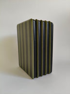 One More Chapter Premium Kindle Case in Midnight Library – six olive and dark green stripe folios fanned upright, front cover view showing black inner edge