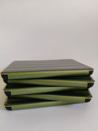 One More Chapter Premium Kindle Case in Midnight Library – five dark green stripe folios stacked flat, side-on view showing black corner detail