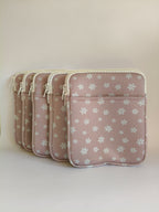 One More Chapter E-reader Sleeve in Petals & Prologues – five blush pink daisy print padded sleeves lined up, angled front view showing front pocket and white zip