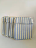 One More Chapter E-reader Sleeve in Rainy Sunday – four periwinkle blue and cream stripe padded sleeves lined up, angled front view showing zip and front pocket