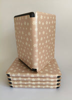 One More Chapter Premium Kindle Case in Petals & Prologues – open folio standing upright on stack of closed cases, blush pink with white floral print