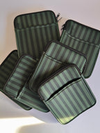 One More Chapter E-reader Sleeve in Midnight Library – five deep forest green tonal stripe sleeves scattered, top-down flat lay