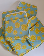 One More Chapter E-reader Sleeve in Lemon Grove – multiple sky blue lemon slice print sleeves scattered, top-down flat lay