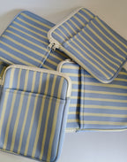 One More Chapter E-reader Sleeve in Rainy Sunday – four periwinkle blue and cream stripe sleeves scattered, top-down flat lay