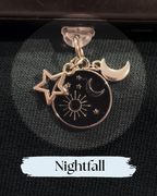 Dust plug for Kindle or e-reader, A celestial charm pendant with a black enamel center featuring sun, moon, and star designs, alongside two dangling star and moon charms, for Kndle, Kindle Accessory, One More Chapter